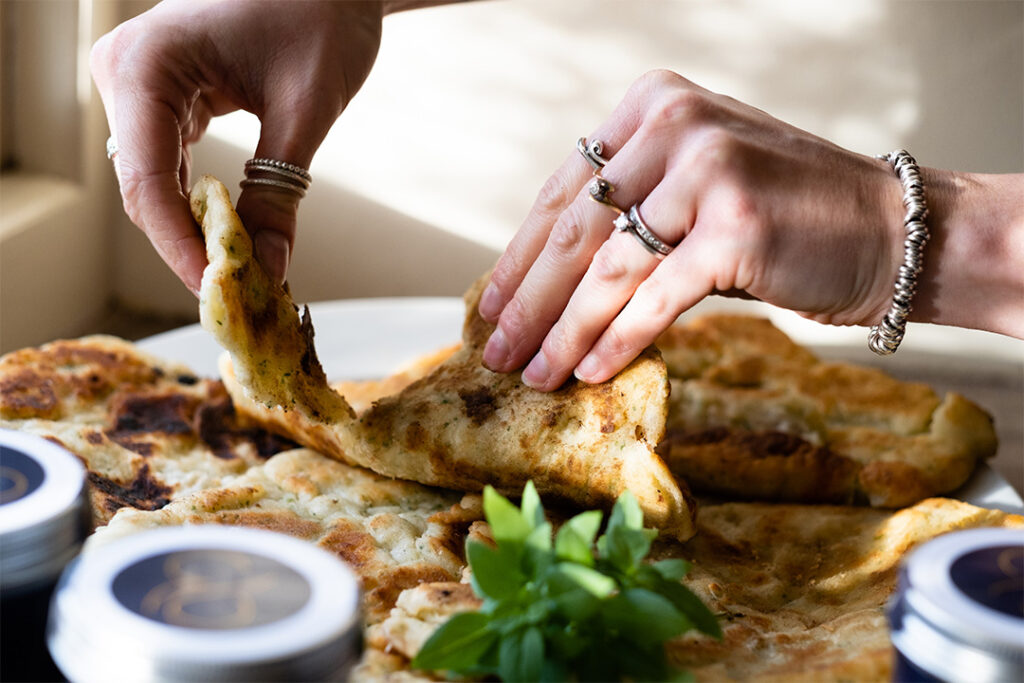 Close up of woman's hands tearing apart thick yoghurt flatbreads