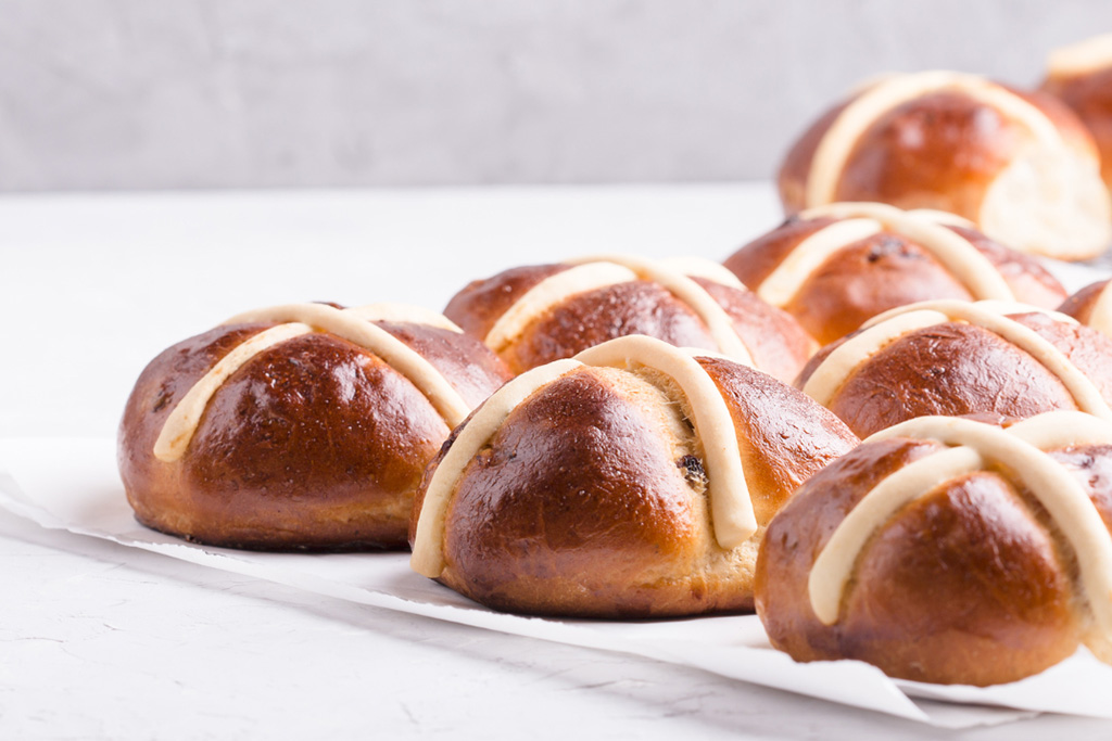 Savoury hot cross buns with golden brown appearance on counter against plain white background